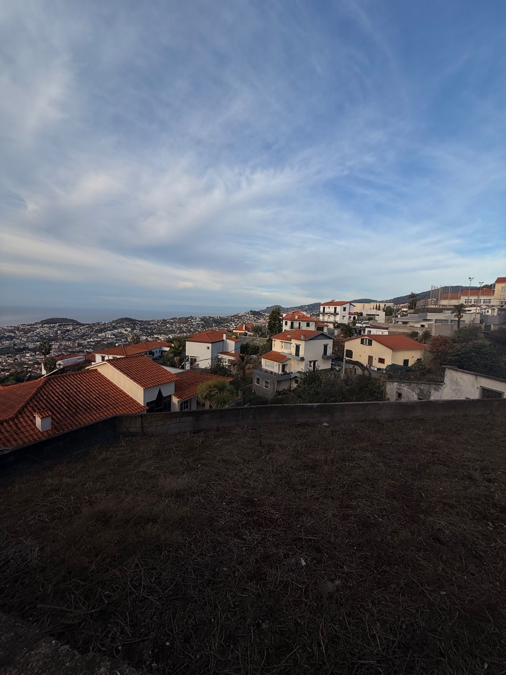 Red-tiled houses on a hillside overlooking densely built slopes and the sea