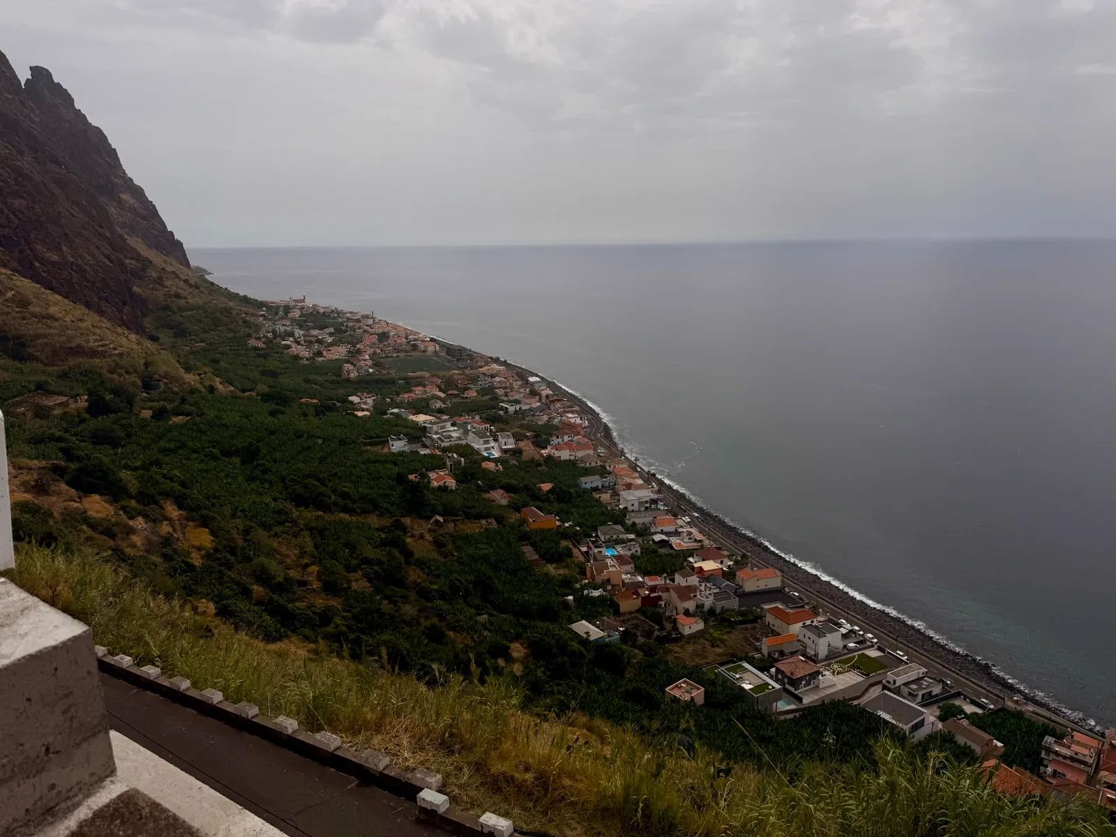 Paul do Mar seen from the cliff road above: a long strip of houses and banana plots between the cliffs and the Atlantic