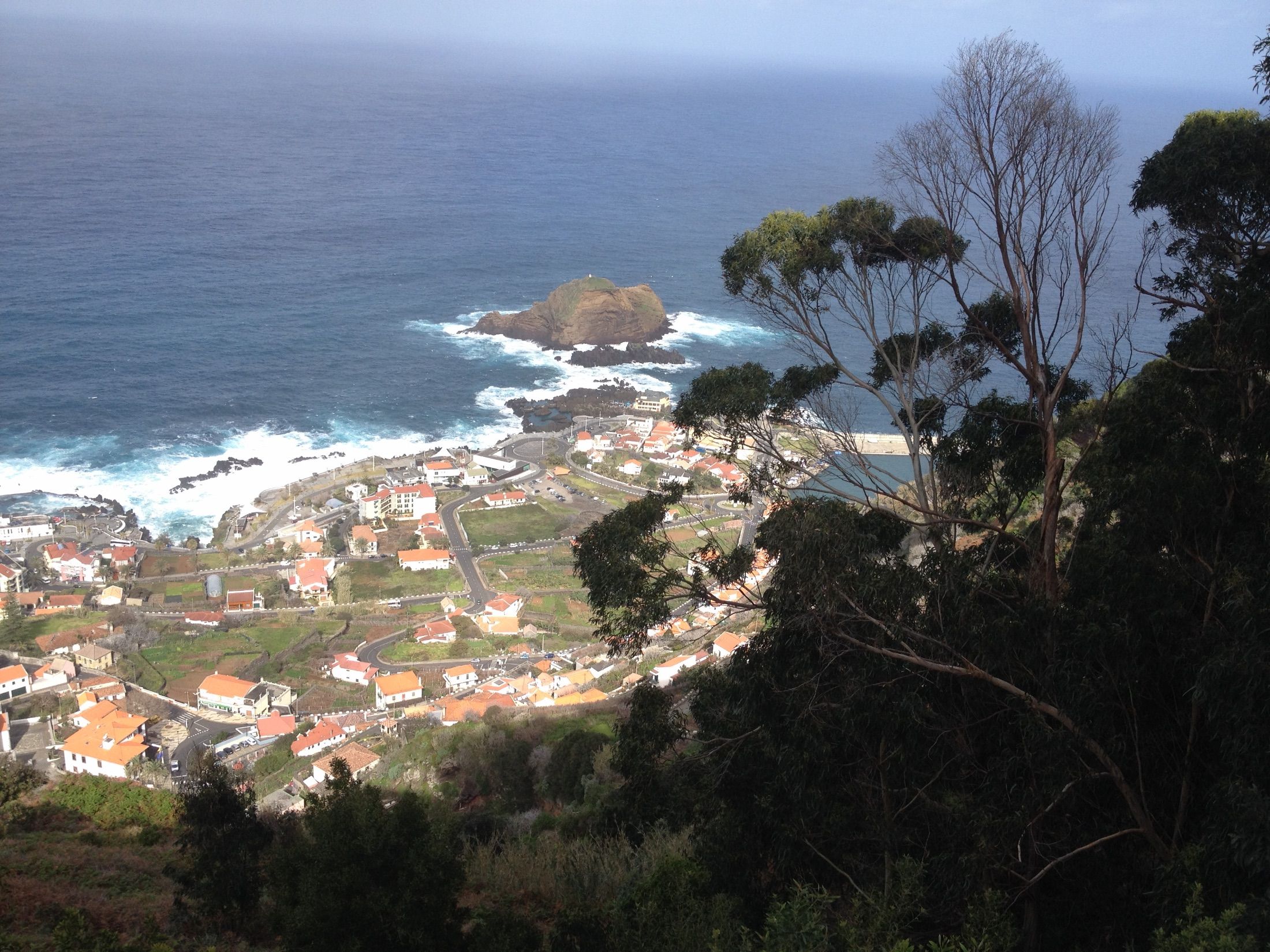 Porto Moniz visto de cima, com casas de telhados vermelhos, costa rochosa e um ilhéu