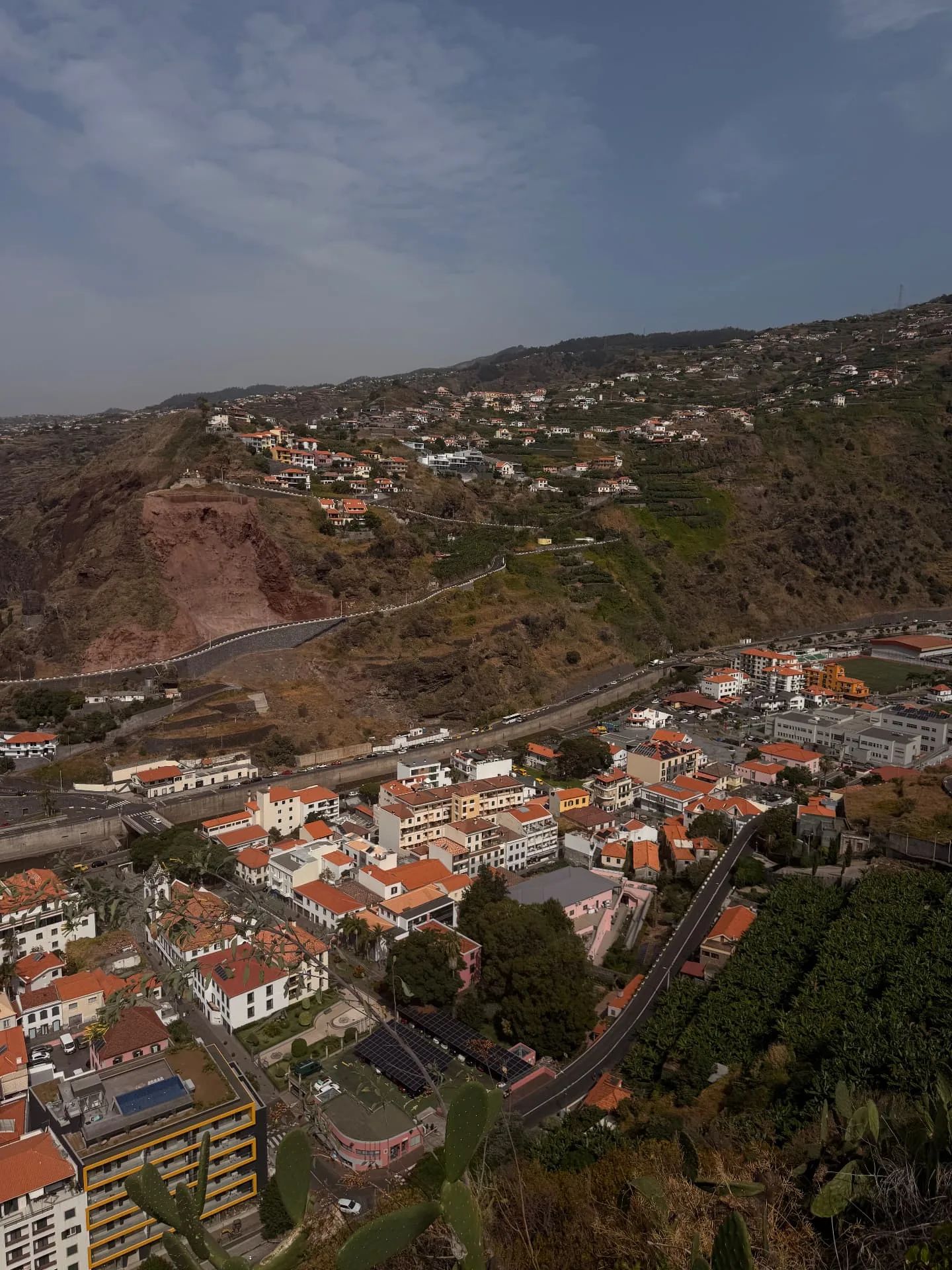 Vista sobre a vila da Ribeira Brava e a estrada do vale, com casas e terraços de bananeiras a subir pela encosta oposta