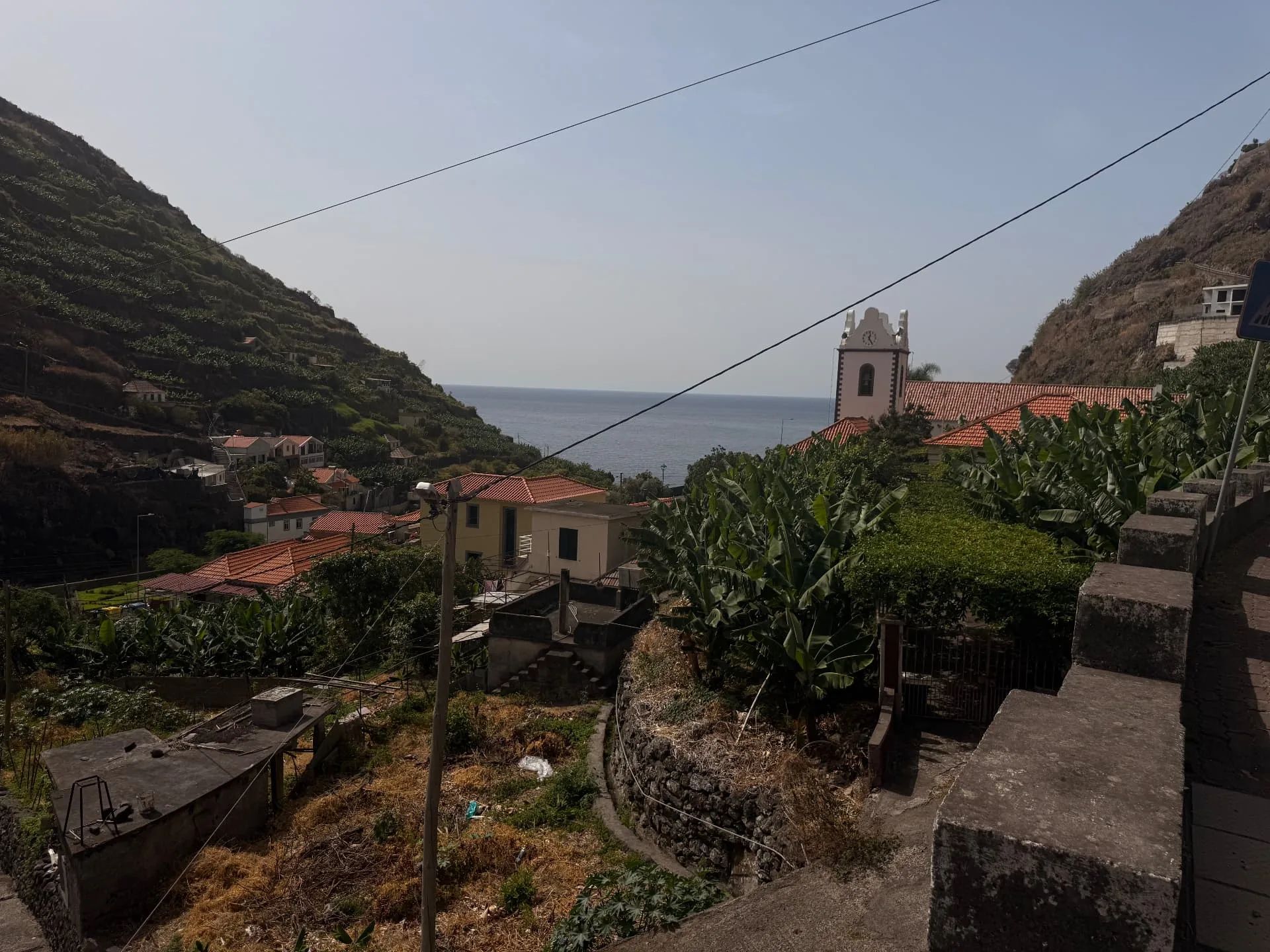 Tabua valley opening to the sea, with terraced banana slopes and the church tower