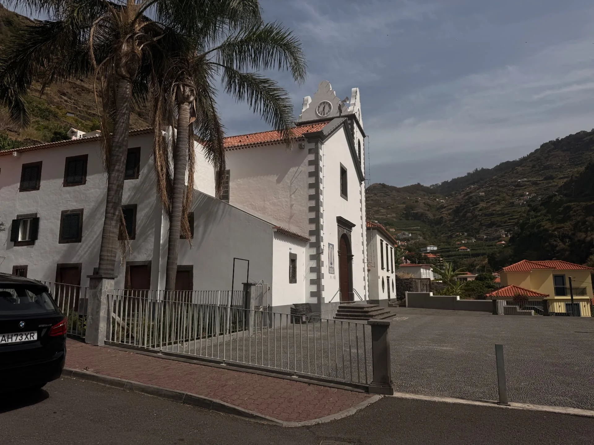 A igreja paroquial de Tabua, com a sua torre do relógio, as palmeiras e a praça do adro