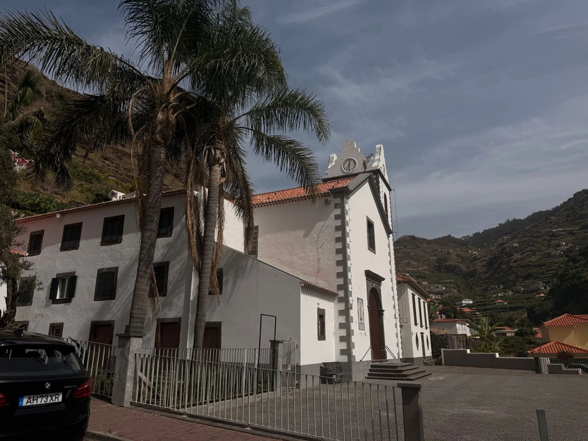 A igreja de Tabua, pintada de branco, e a casa vizinha, sob palmeiras altas