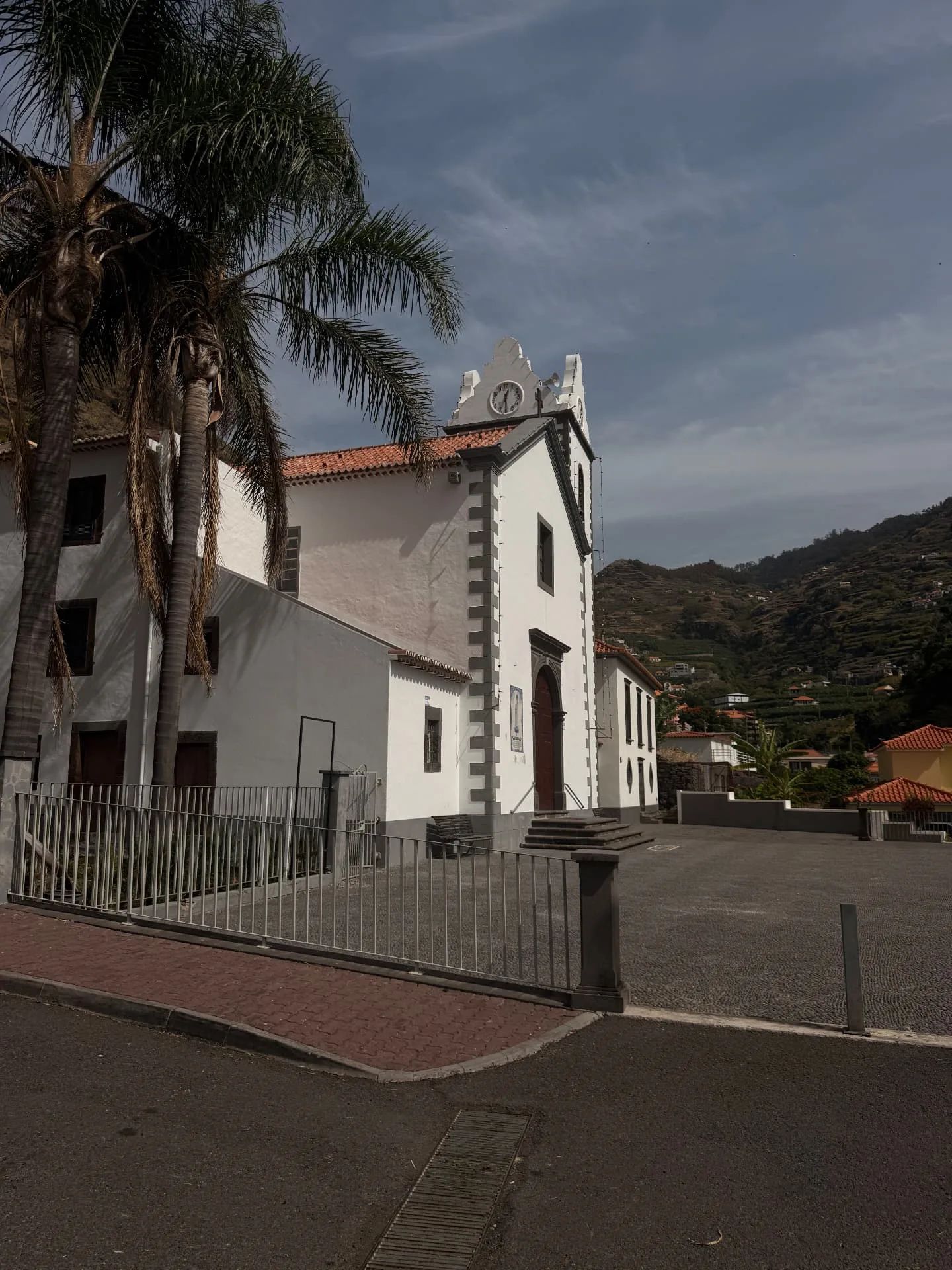Fachada da igreja de Tabua, com acabamentos em pedra cinzenta, e o vale em socalcos ao fundo