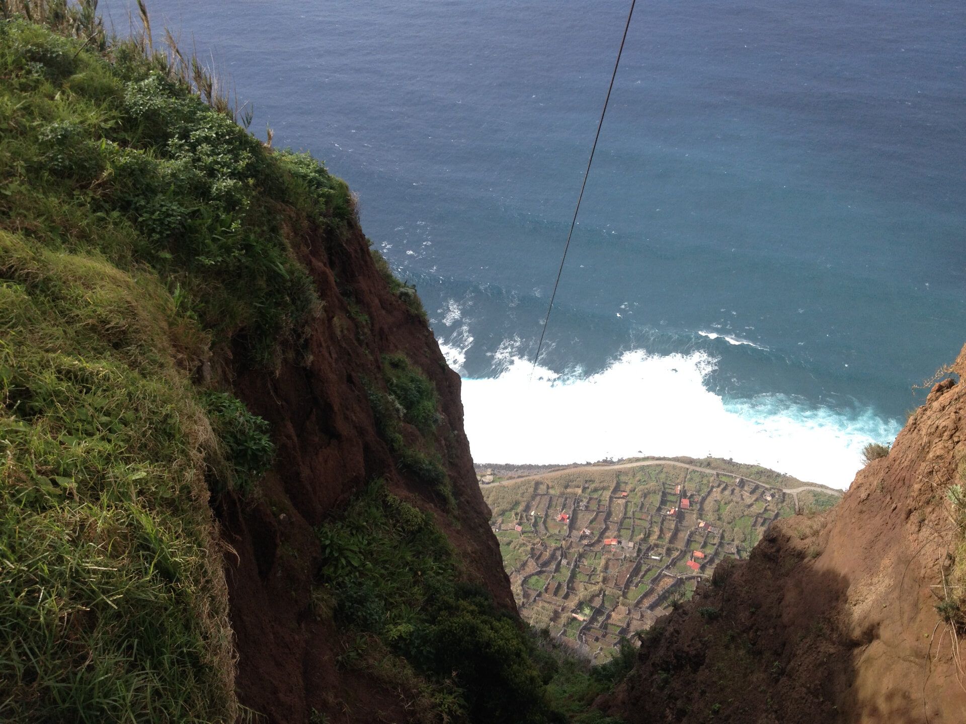 Achadas da Cruz cable car descending the red-earth ravine to the fajã