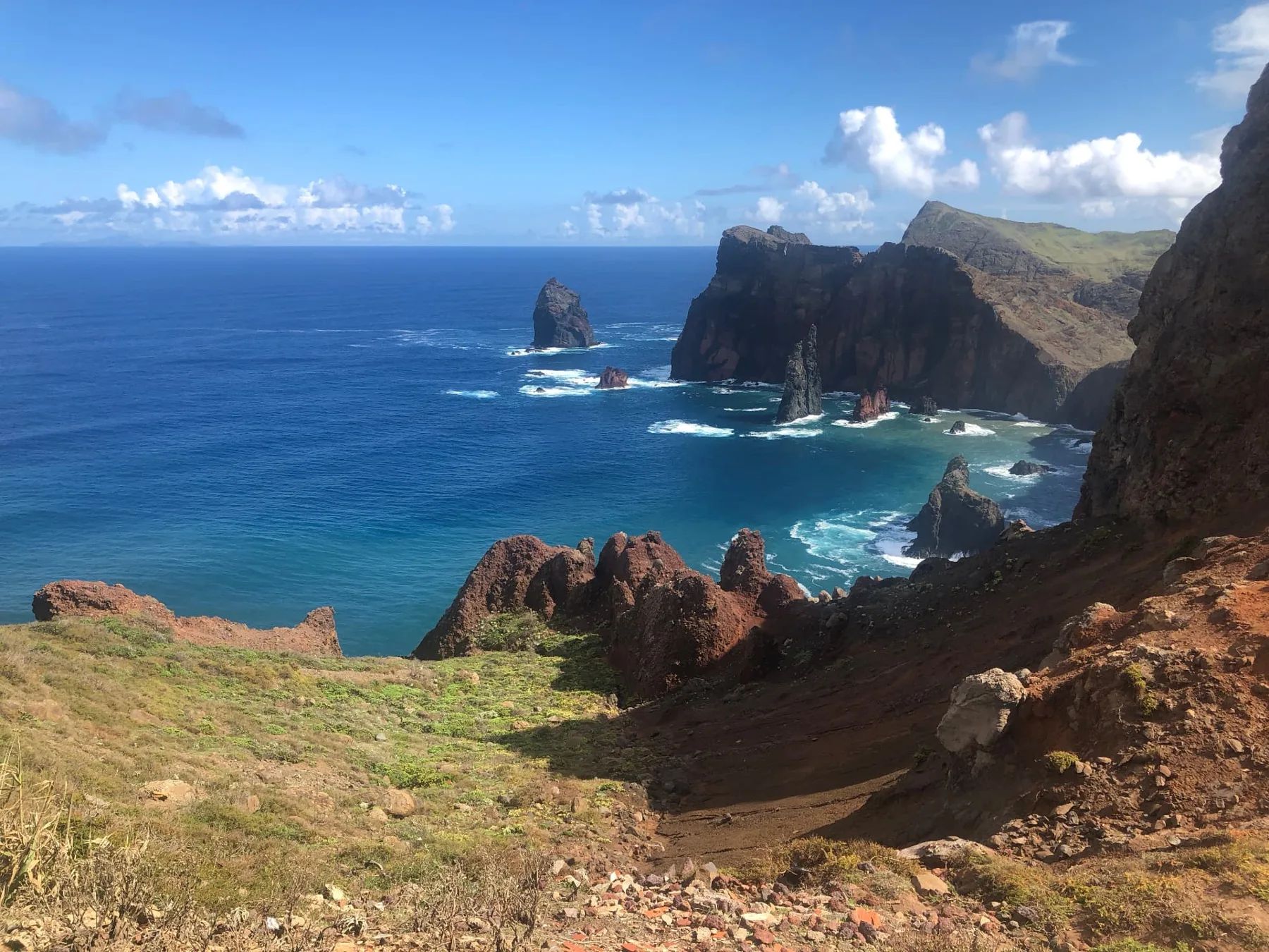 Formações rochosas no mar e rocha vulcânica vermelha ao pé das falésias da Ponta de São Lourenço num dia de sol