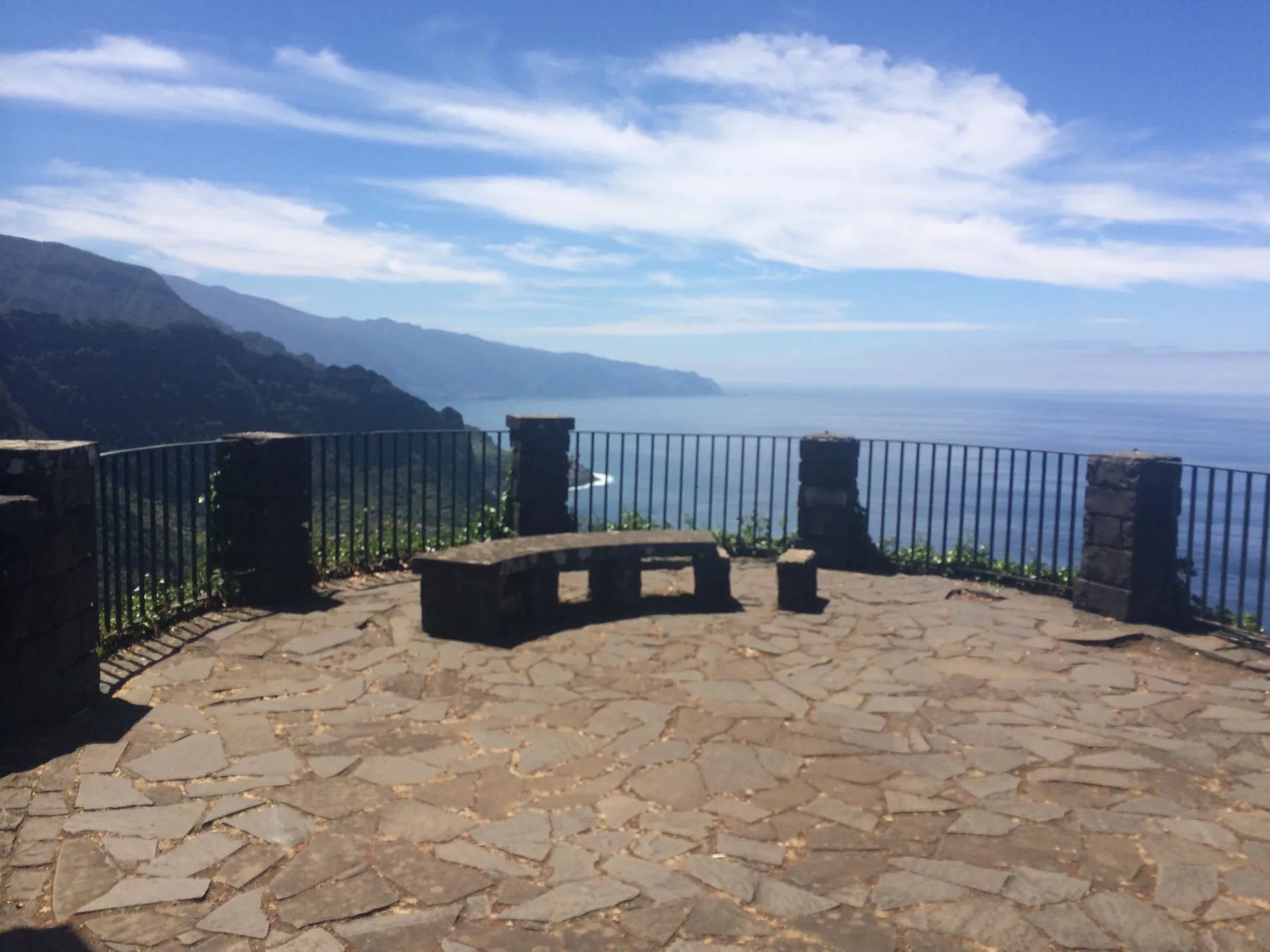 Stone-paved viewing terrace with a curved bench and railings at Miradouro das Cabanas