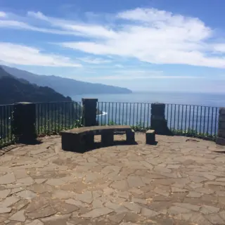 Stone-paved viewing terrace with a curved bench and railings at Miradouro das Cabanas