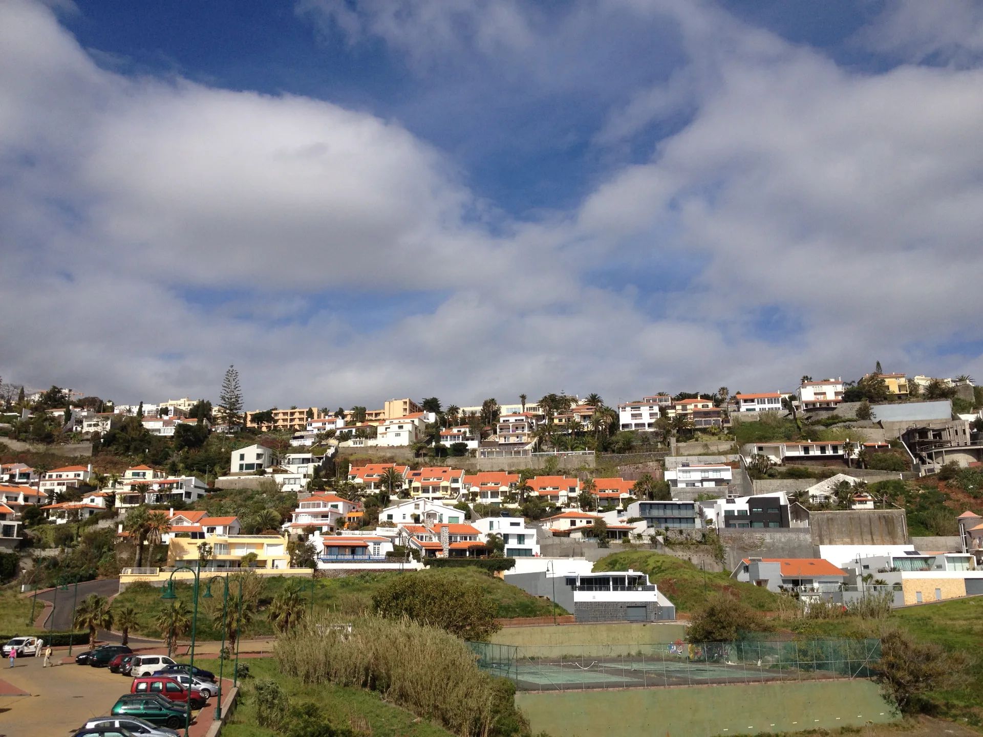 Free car park at the Cristo Rei viewpoint in Garajau with parked cars and the village on the hillside above