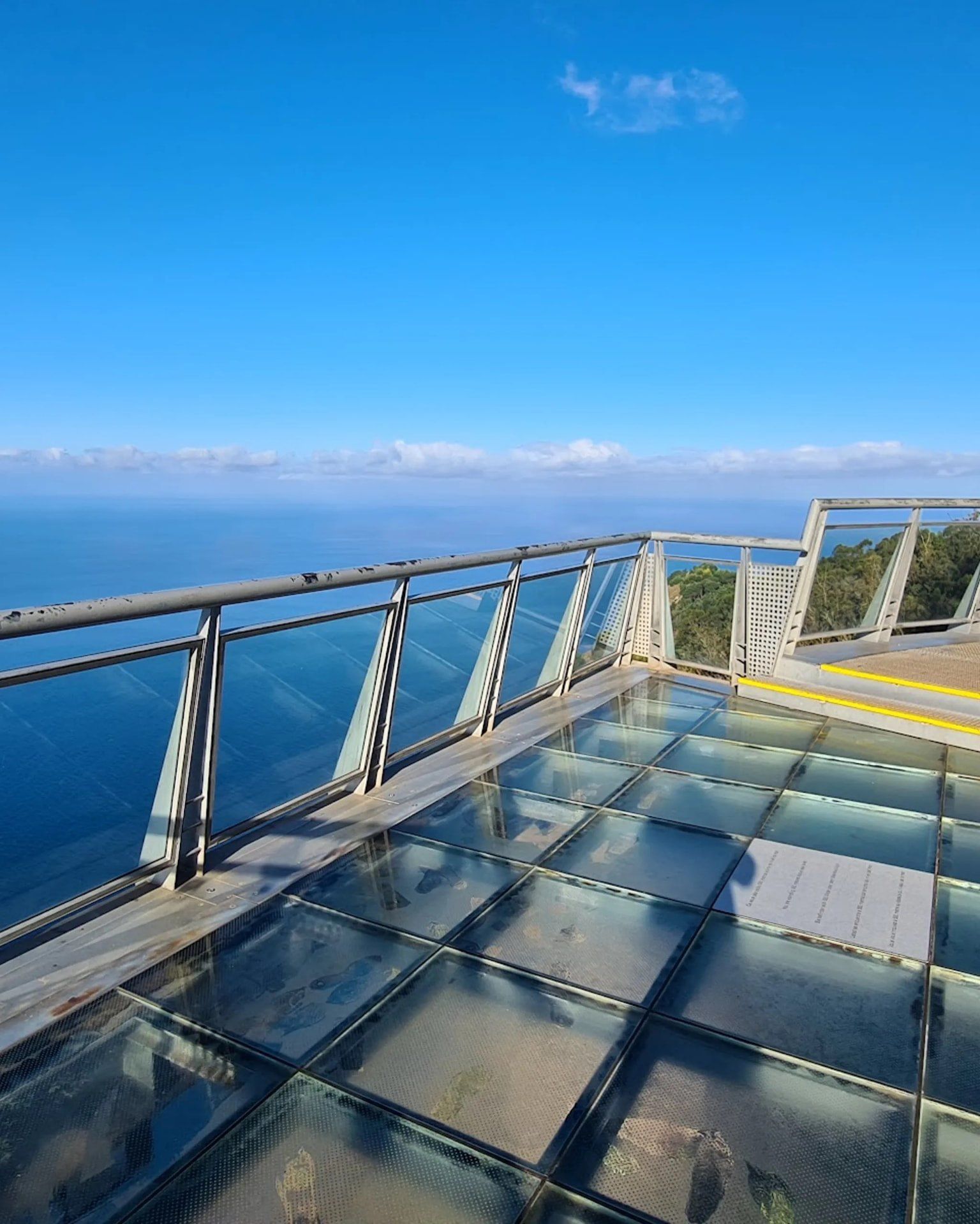 Glass floor panels of the Cabo Girão skywalk with the Atlantic 580 m below and blue sky above, Madeira