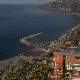 View from Miradouro de São Sebastião down onto Ribeira Brava beach, the breakwater, the seafront pool and the south coast cliffs